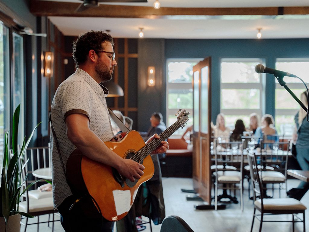 Bradley Kerr playing acoustic guitar during a live performance.