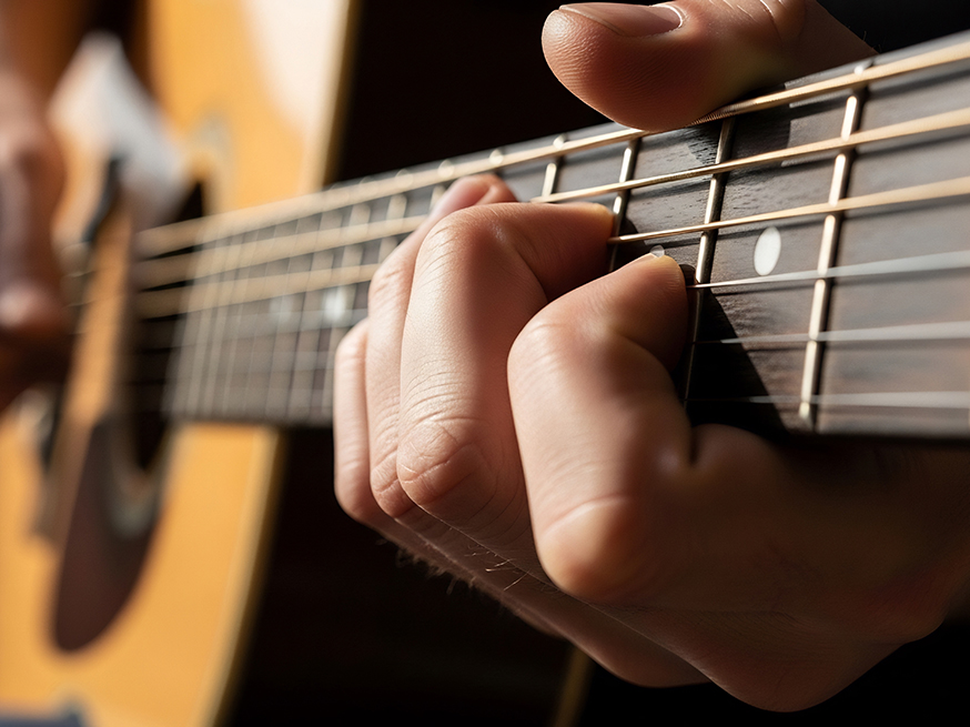 closeup of a persons hands playing an acoustic guitar